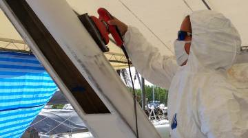 Amanda in a bunny suit, sanding a ridge off the targa-bar