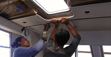 Houa and Baw test-installing a headliner over the galley