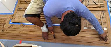 Houa, foot bandaged, works on the starboard side of the cockpit