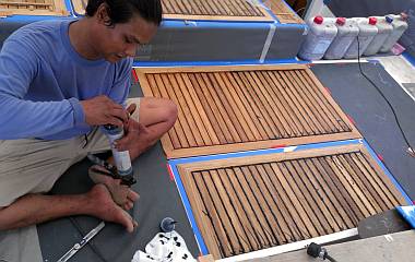 Houa calking 2 sections of teak flooring in the cockpit