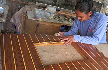 Houa sanding down a tight floorboard in his workshop