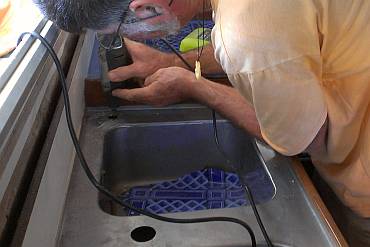 Dremeling open a hole for a faucet in the galley sink