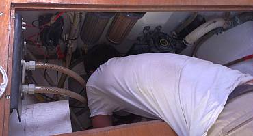 Jon upside down in the watermaker bilge, repairing a hose