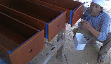 Lek varnishing the fronts of some long drawers