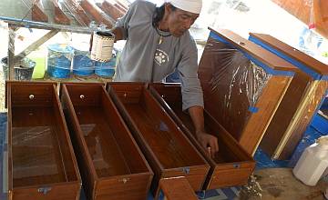 Lek brushes satin varnish on a set of long drawers