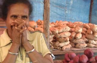 Hiding a smile. Potato seller in Timor, Indonesia