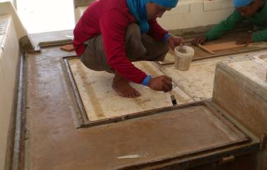 Mee laying glass strips against Houa's small wooden frames