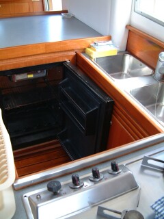 Old galley fridge, with door open, before the conversion.  Note holding plate at top.