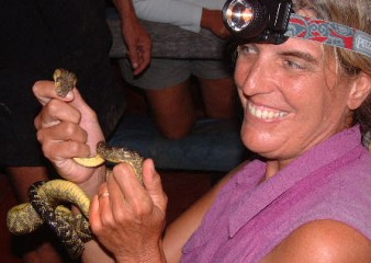 Sue handles a wild boa picked from a tree at night on the Apure River.