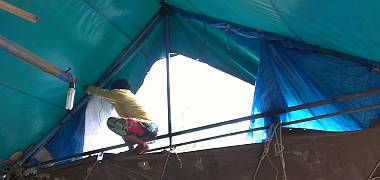 Yando perched at the top of Houa's workshop, replacing a tarp