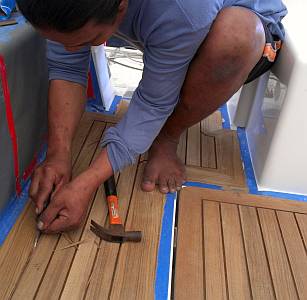 Cleaning out the grooves between the teak planks