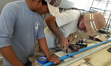 Heru and Jon cut holes in the sides of the wiring conduit